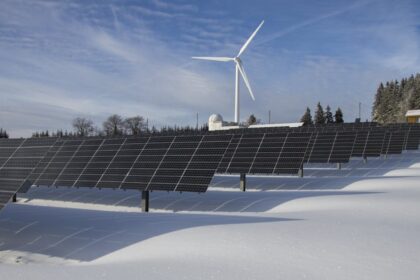 Solar panels and wind turbine in a snowy landscape, showcasing renewable energy sources.