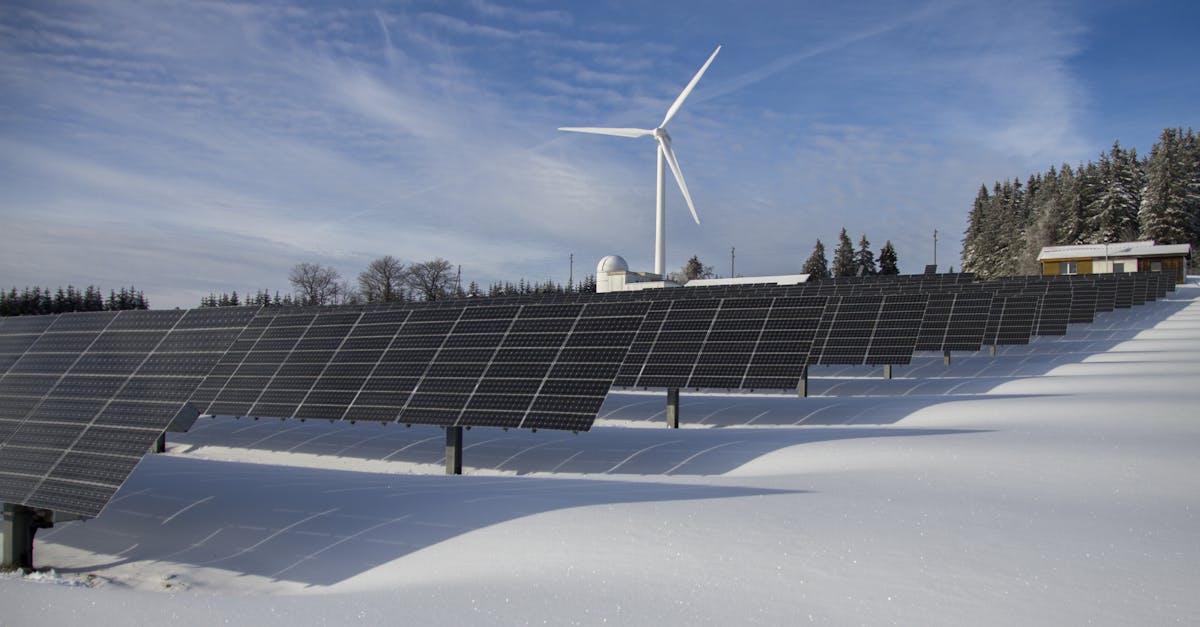 Solar panels and wind turbine in a snowy landscape, showcasing renewable energy sources.