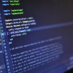 Close-up of a computer screen displaying programming code in a dark environment.