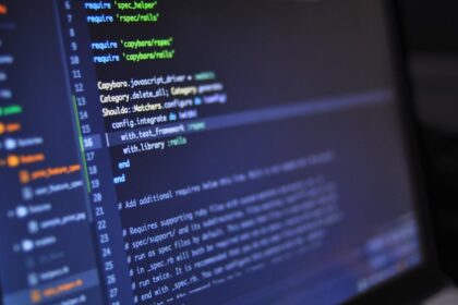 Close-up of a computer screen displaying programming code in a dark environment.