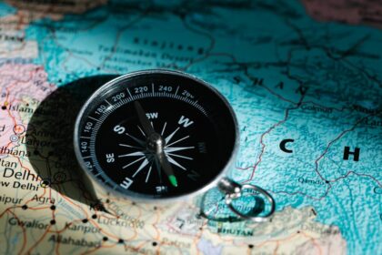 A compass resting on a map of China and India signifies exploration and adventure.